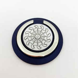 May include: A silver phone ring holder with a navy blue outer ring. The silver ring has a circular design with the word "Julie" repeated in a circular pattern.