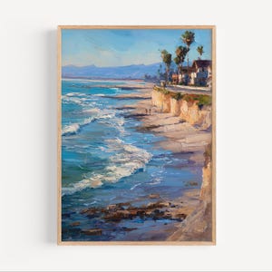May include: Oil painting of a coastal scene with a beach, ocean waves, and cliffs. The artwork features a bright blue sky, turquoise water, and a sandy beach. The painting is framed in a light brown wooden frame.