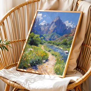 May include: A framed painting of a mountain landscape with a river flowing through it. The painting is in a wooden frame and is sitting on a wicker chair.
