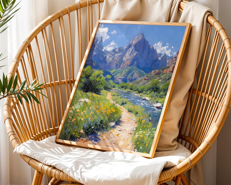 May include: A framed painting of a mountain landscape with a river flowing through it. The painting is in a wooden frame and is sitting on a wicker chair.