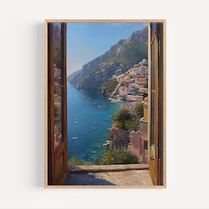 May include: A framed print of a coastal Italian town viewed through an open window. The artwork depicts a vibrant scene with colorful buildings, a turquoise sea, and lush green mountains under a clear blue sky. The wooden window frame adds a natural touch.