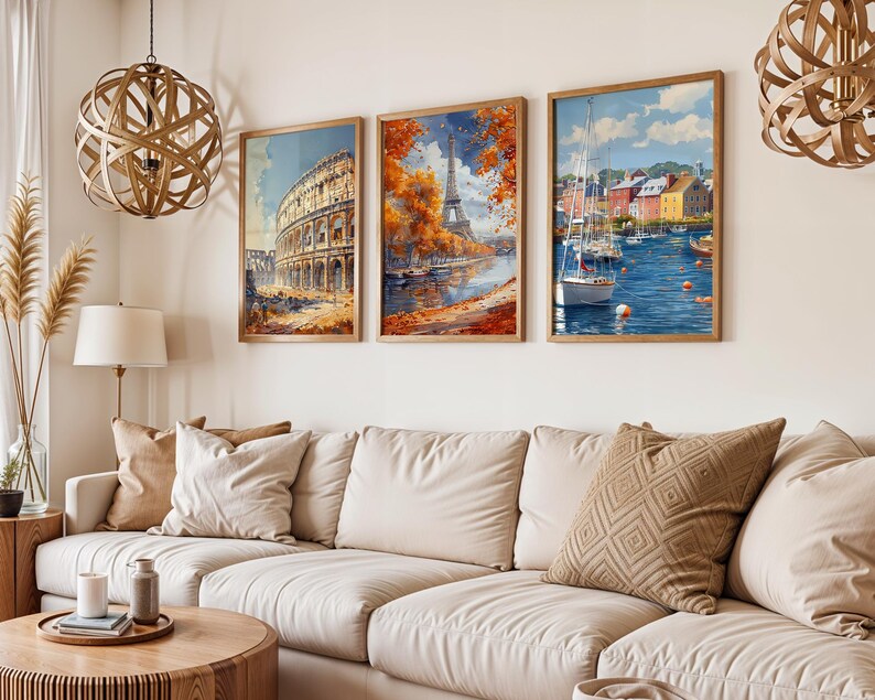 May include: Three framed watercolor prints depicting European landmarks. The first shows the Colosseum, the second the Eiffel Tower, and the third a harbor scene with boats. The prints are in wooden frames and hang above a cream-colored sofa.