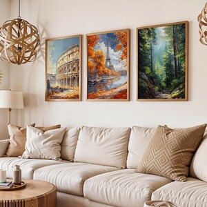 May include: Three framed art prints depicting iconic landmarks and a forest scene. The first print shows the Colosseum in Rome, the second the Eiffel Tower in Paris, and the third a lush forest path. The prints are displayed above a cream-colored sofa.