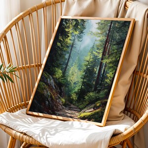 May include: A framed landscape art print depicting a forest scene with tall trees and a path. The artwork features a palette of greens, browns, and blues, with sunlight filtering through the trees. The frame is made of light-colored wood.