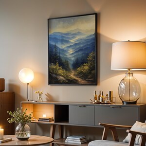 May include: A living room interior with a gray couch, a wooden coffee table, a side table with a lamp, and a framed painting of a mountain landscape. The painting is in a black frame and features a blue and green color scheme.