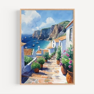May include: A watercolor painting of a coastal village with white houses and terracotta roofs. The houses are built on a hillside overlooking a blue ocean with sailboats. The scene is framed by a wooden frame.