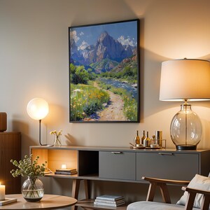 May include: A living room interior with a gray couch, a wooden coffee table, a side table with a lamp, and a large framed painting of a mountain landscape with a river running through it.