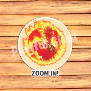 Op de afbeelding: Een ronde sticker met een superheld die in vlammen gehuld is. De superheld draagt een rood-wit pak met een nummer "4" op de borst. De sticker heeft de tekst "ZOOM IN!" eronder gedrukt.