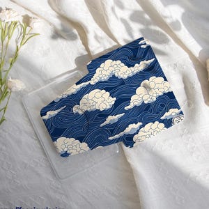 May include: A navy blue phone case featuring a cloud and wave pattern. The design includes white and light blue clouds against a background of wavy lines. The text "happylifeenjoydesign" is printed at the bottom.