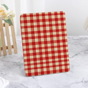 Op de afbeelding: Rode en witte geruite iPad-hoes. De hoes is gemaakt van zacht, duurzaam materiaal en heeft een slank ontwerp.