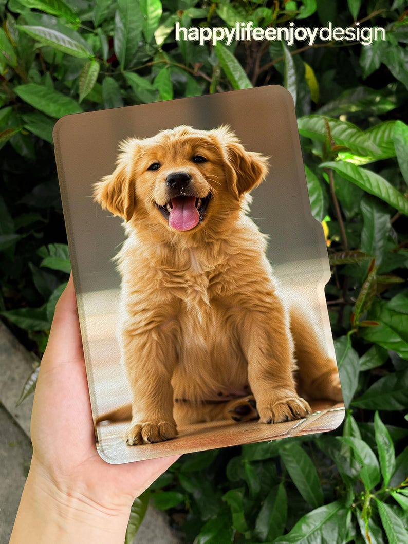 Puede incluir: Una funda para tableta con la imagen de un cachorro de golden retriever sonriente con la lengua fuera. La funda tiene un fondo marr&oacute;n y el texto "happylifeenjoydesign" en blanco. La funda se sostiene contra un fondo de hojas verdes.