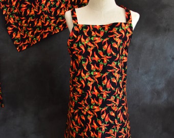 May include: A black apron with a red chili pepper print. The apron has adjustable straps and a large pocket in the front.