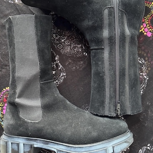May include: Black suede ankle boots with a chunky rubber sole and a zipper up the back. The boots have a pull-on style and a slightly pointed toe.
