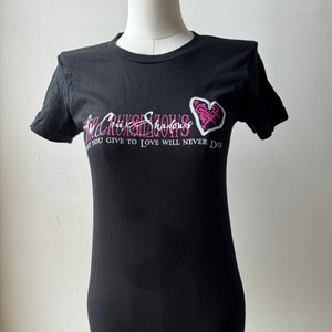 May include: Black t-shirt with a pink heart and white text that reads "The Crimsonshadows What you give to love will never die."
