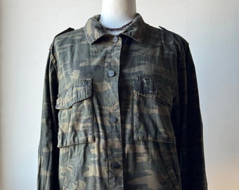 May include: A green, brown, and black camouflage print button-up shirt with long sleeves and a frayed hem.