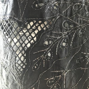 May include: Black fabric with intricate cut-out and embroidered floral designs. The fabric has a delicate, lacy appearance.