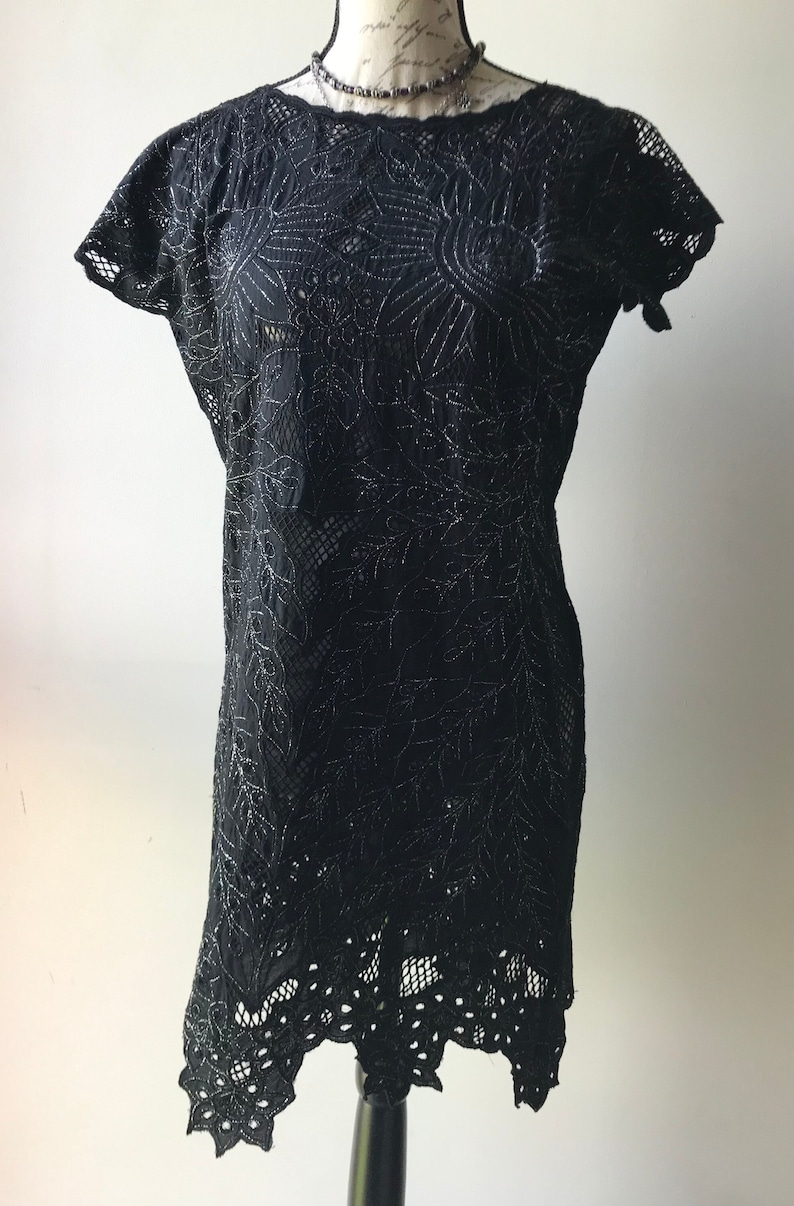 May include: Black lace dress with a silver embroidered floral pattern and a scalloped hem.