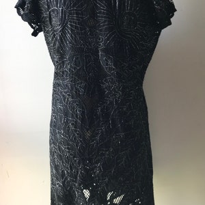 May include: Black lace dress with a floral pattern and a scalloped hem.