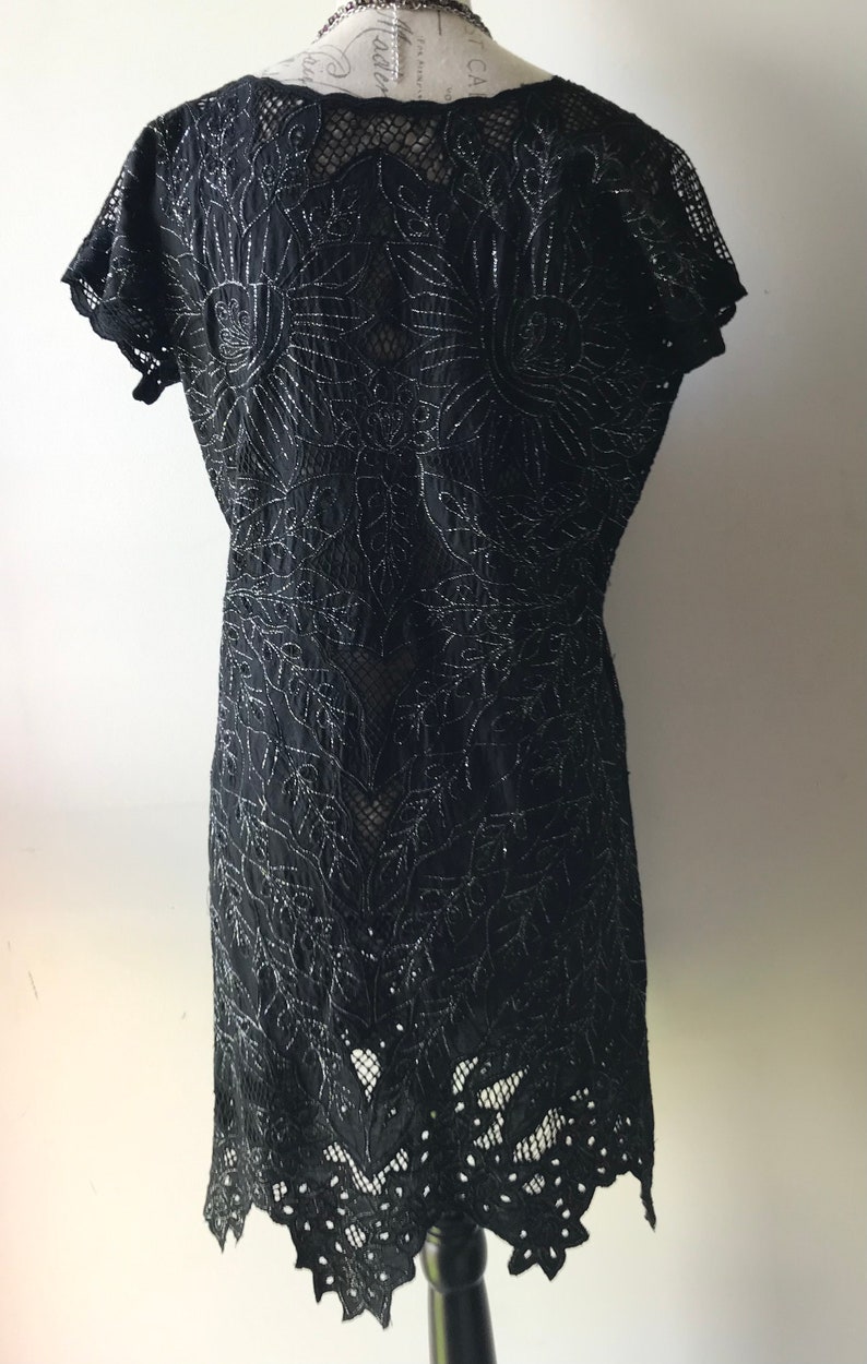 May include: Black lace dress with a floral pattern and a scalloped hem.