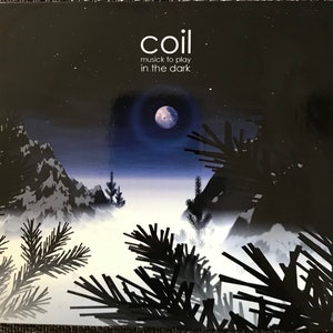 May include: Album cover for "coil musick to play in the dark." The artwork depicts a night scene in dark blue and black, with a full moon, mountains, and silhouetted pine trees. The band's name, "coil," is in white text at the top.