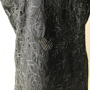 May include: Black sheer top with silver embroidery of a floral pattern.