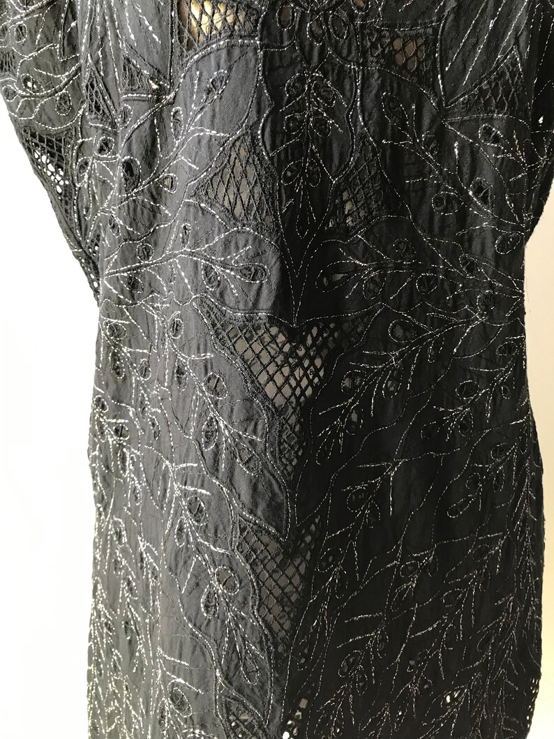 May include: Black sheer top with silver embroidery of a floral pattern.