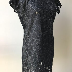 May include: A black lace dress with silver embroidery. The dress has a round neckline and short sleeves. The lace is delicate and intricate, and the embroidery is a floral design.