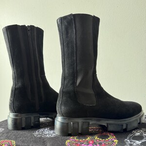 May include: A pair of black suede knee-high boots with a chunky platform sole and a zipper on the back.