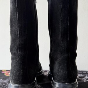 May include: A pair of black suede knee-high boots with a zipper on the side and a chunky heel.