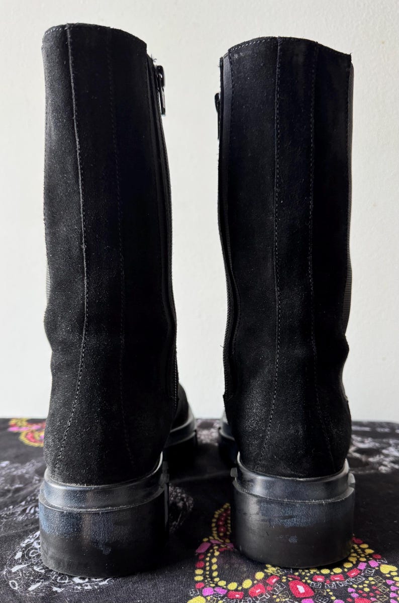 May include: A pair of black suede knee-high boots with a zipper on the side and a chunky heel.
