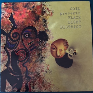 May include: Album cover for "COIL presents BLACK LIGHT DISTRICT." The artwork features abstract shapes and a portrait of a person with a large head. The colour palette includes red, black, gold, and beige.