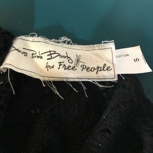 May include: A white tag with black text that reads "Boots for Free People" with a dragonfly graphic. The tag also has a smaller white tag that reads "Cotton" and "S".