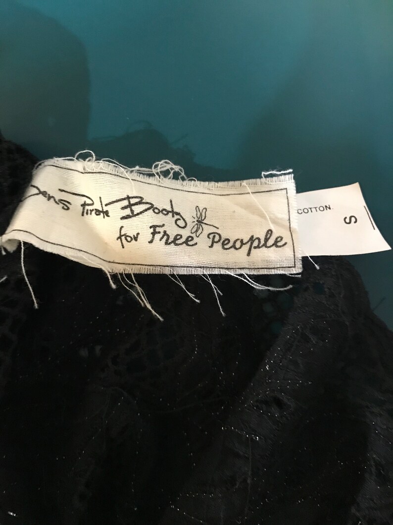 May include: A white tag with black text that reads "Boots for Free People" with a dragonfly graphic. The tag also has a smaller white tag that reads "Cotton" and "S".