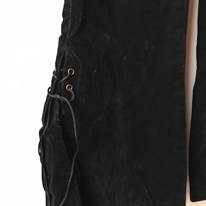 K&ouml;nnte beinhalten: Schwarze Samt-Hose mit Schn&uuml;rung an der Seite. Die Schn&uuml;re sind schwarz und haben goldene &Ouml;sen.