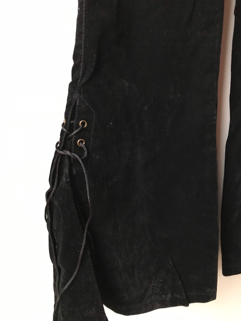 K&ouml;nnte beinhalten: Schwarze Samt-Hose mit Schn&uuml;rung an der Seite. Die Schn&uuml;re sind schwarz und haben goldene &Ouml;sen.