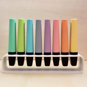 Peut inclure: Un ensemble de huit surligneurs de couleur pastel dans un support blanc. Les couleurs sont vert menthe, vert lime, bleu clair, gris, lavande, rose, pêche et jaune.