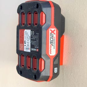Peut inclure: Un chargeur de batterie Parkside X20V Team rouge et noir avec un marquage CE et un code QR. Le chargeur est doté d'un support mural et d'un bouton d'alimentation.