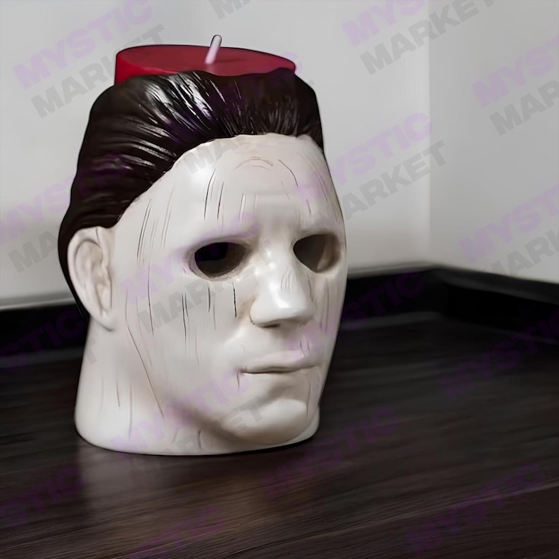 K&ouml;nnte beinhalten: Eine wei&szlig;e Keramikkopfskulptur mit dunkelbraunem Haar und einer roten Kerze oben. Die Skulptur hat ein leeres, ausdrucksloses Gesicht mit vertikalen Linien. Die Kerze ist rot mit einem wei&szlig;en Docht. Die Skulptur steht auf einer dunkelbraunen Oberfl&auml;che.