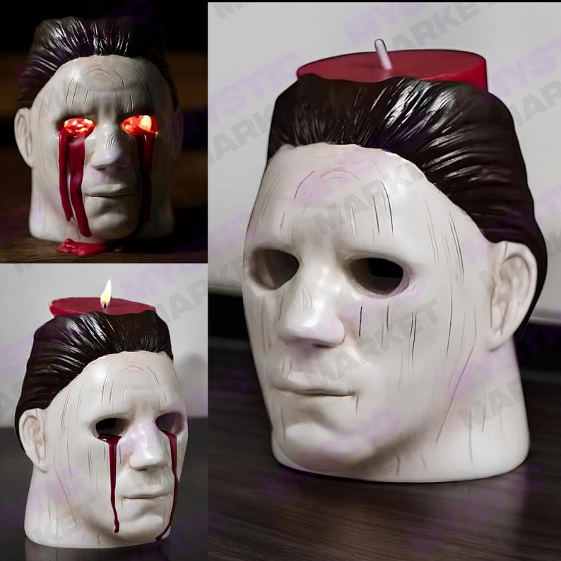 K&ouml;nnte beinhalten: Ein wei&szlig;er Kerzenhalter in Maskenform mit dunkelbraunem Haar. Auf der Oberseite der Maske befindet sich eine rote Kerze, und rotes Wachs tropft das Gesicht hinunter. Auf einem Bild leuchten die Augen rot.