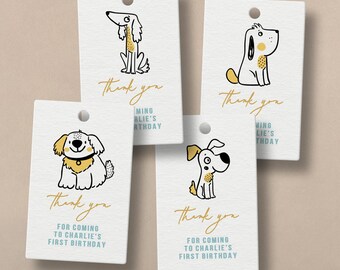 May include: Four cream-colored gift tags with illustrated cartoon dogs. Each tag has the words "Thank you" in gold script, and the text "For coming to Charlie's first birthday" in a blue font. The tags have a hole at the top.