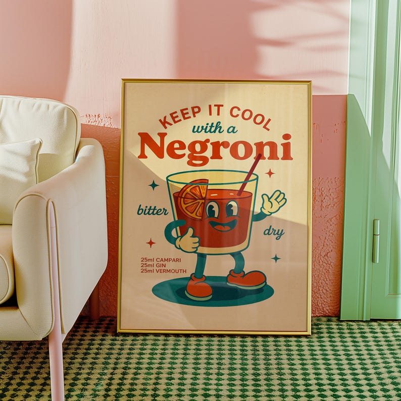以下が含まれることがあります： 「KEEP IT COOL with a Negroni」の文字が入った、額縁に入ったヴィンテージスタイルのポスター。イラストは、笑顔の顔、オレンジスライス、ストローが付いた漫画のカクテルグラスです。ポスターには、材料としてカンパリ25ml、ジン25ml、ベルモット25mlが含まれています。