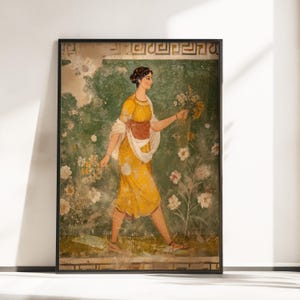 May include: Framed print of an ancient fresco depicting a woman in a yellow dress holding flowers. The artwork features a green and white floral background and is framed in black.