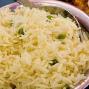 May include: A bowl of white rice with green peas, a common side dish in Indian cuisine.
