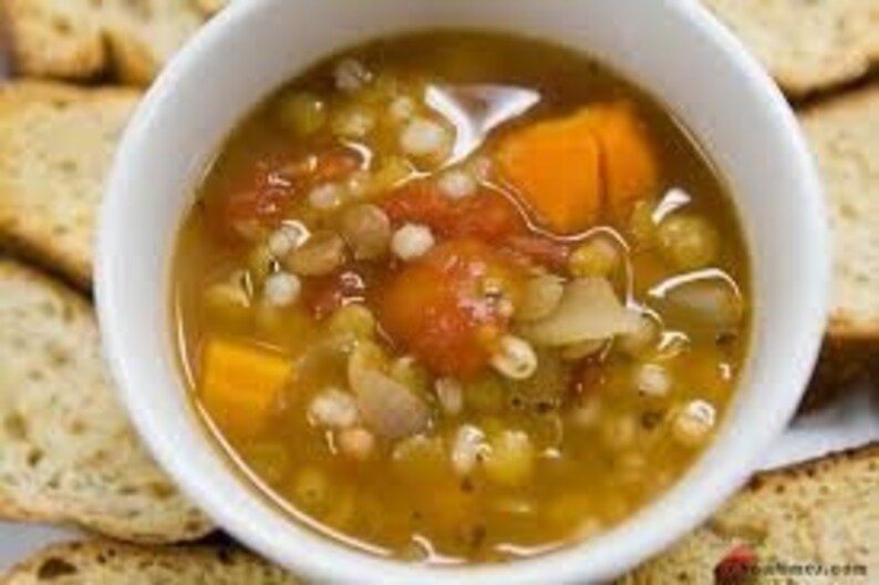 May include: A bowl of hearty lentil soup with barley, sweet potato, and tomatoes. The soup is a vibrant orange color and is garnished with fresh herbs. The soup is served with toasted bread.