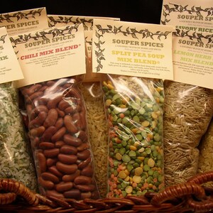 May include: Six clear plastic bags filled with different dry soup and rice mixes. The bags are labeled with the name "Souper Spices" and the type of mix inside. The mixes include "Dry Rice Mix Blend", "Chili Mix Blend", "Split Pea Soup Mix Blend", "Savory Rice Mix", "Lemon Herb Rice Mix Blend".