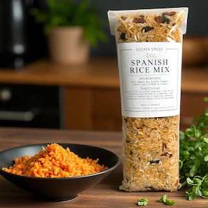 May include: A clear bag of Souper Spices Spanish Rice Mix with a white label displaying ingredients and directions. A black bowl of cooked orange rice sits next to the bag. The bag contains 8.0 oz of rice mix.
