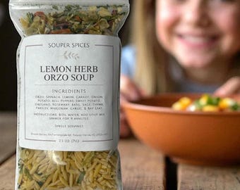 Peut inclure: Un sachet en plastique transparent contenant le mélange pour soupe Souper Spices Lemon Herb Orzo Soup. L'étiquette indique les ingrédients : orzo, épinards, citron, carotte, oignon, pomme de terre, poivrons, patate douce, origan, romarin, basilic, sauge.