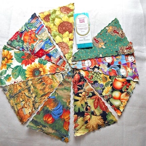 May include: A collection of eight triangular fabric pennants featuring various autumn-themed prints, including sunflowers, pumpkins, and harvest motifs, arranged in a circular pattern with a package of single fold bias tape in bright peacock.