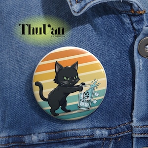 Puede incluir: Un botón redondo con una ilustración de un gato negro sosteniendo un vaso de agua con cubitos de hielo. El vaso tiene el texto "NO ICE PLEASE". El fondo presenta un diseño retro de puesta de sol con rayas naranjas, amarillas y azules.