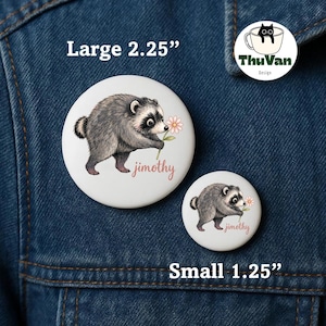 May include: Two round white pinback buttons featuring a gray raccoon holding a pink flower with the name jimothy printed in pink script. The larger button is labeled Large 2.25 inches and the smaller button is labeled Small 1.25 inches.